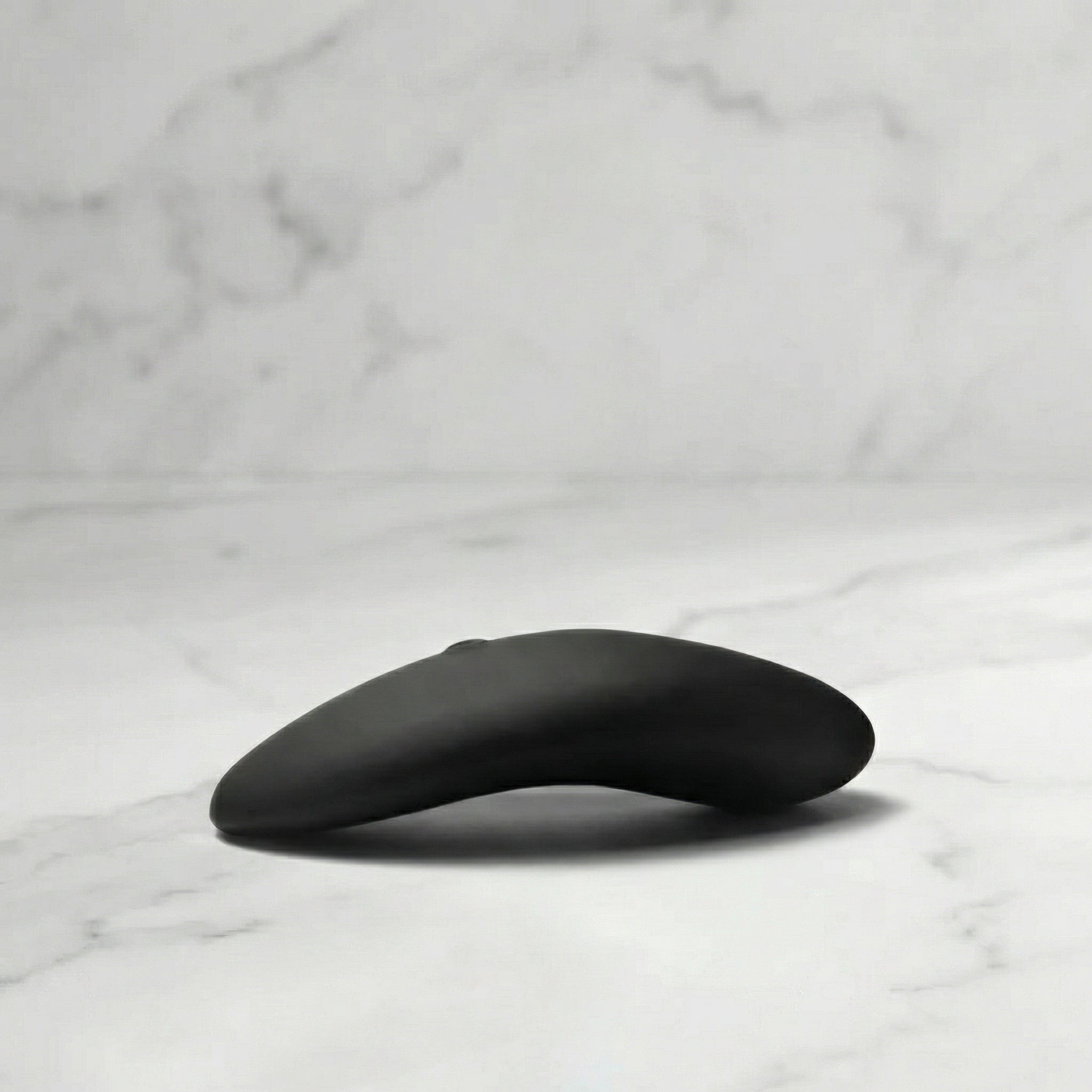 Zwarte Aludra stimulator met gebogen ergonomisch design op marmeren ondergrond
